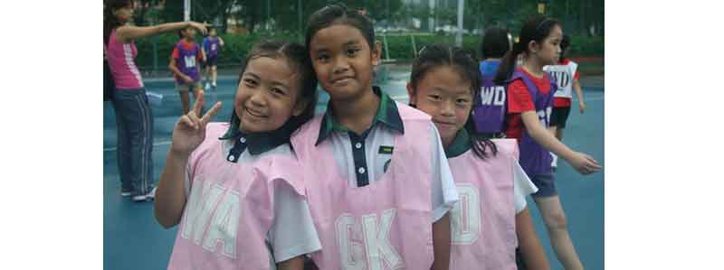 Three young girls with their netball bibs on